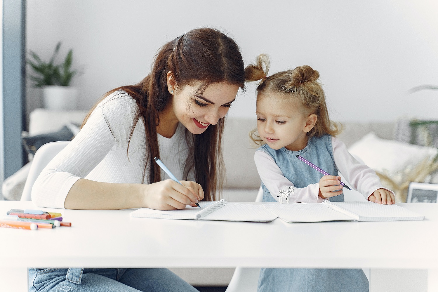 A woman demonstrating to a child how to write