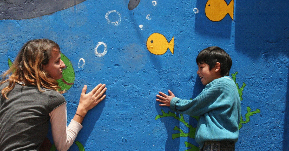 Volunteer in Cusco speaks Spanish with a laughing child while they play